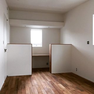 寝室の隅に作られたワークスペース。 集成材で作られた造作カウンターとベッドスペースの間の腰壁は厚みを持たせた造作の本棚になっています。