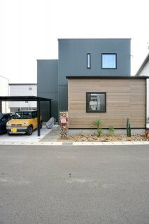 モスグリーンのガルバとウッド調サイディングの家